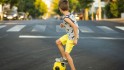 Kleiner Junge spielt Fußball auf der Straße.